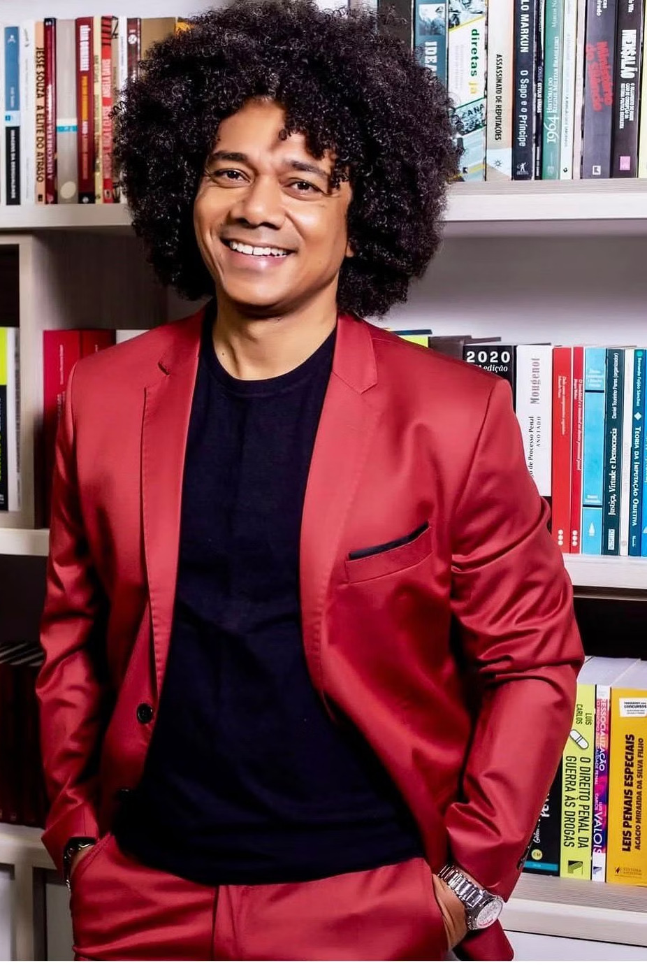 Prof. Marinho Soares com blazer vermelho diante de estante com livros jurídicos